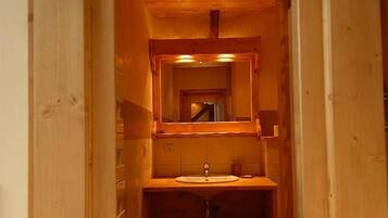 Une salle de bain avec un cadre en bois, comprenant un lavabo et un miroir.