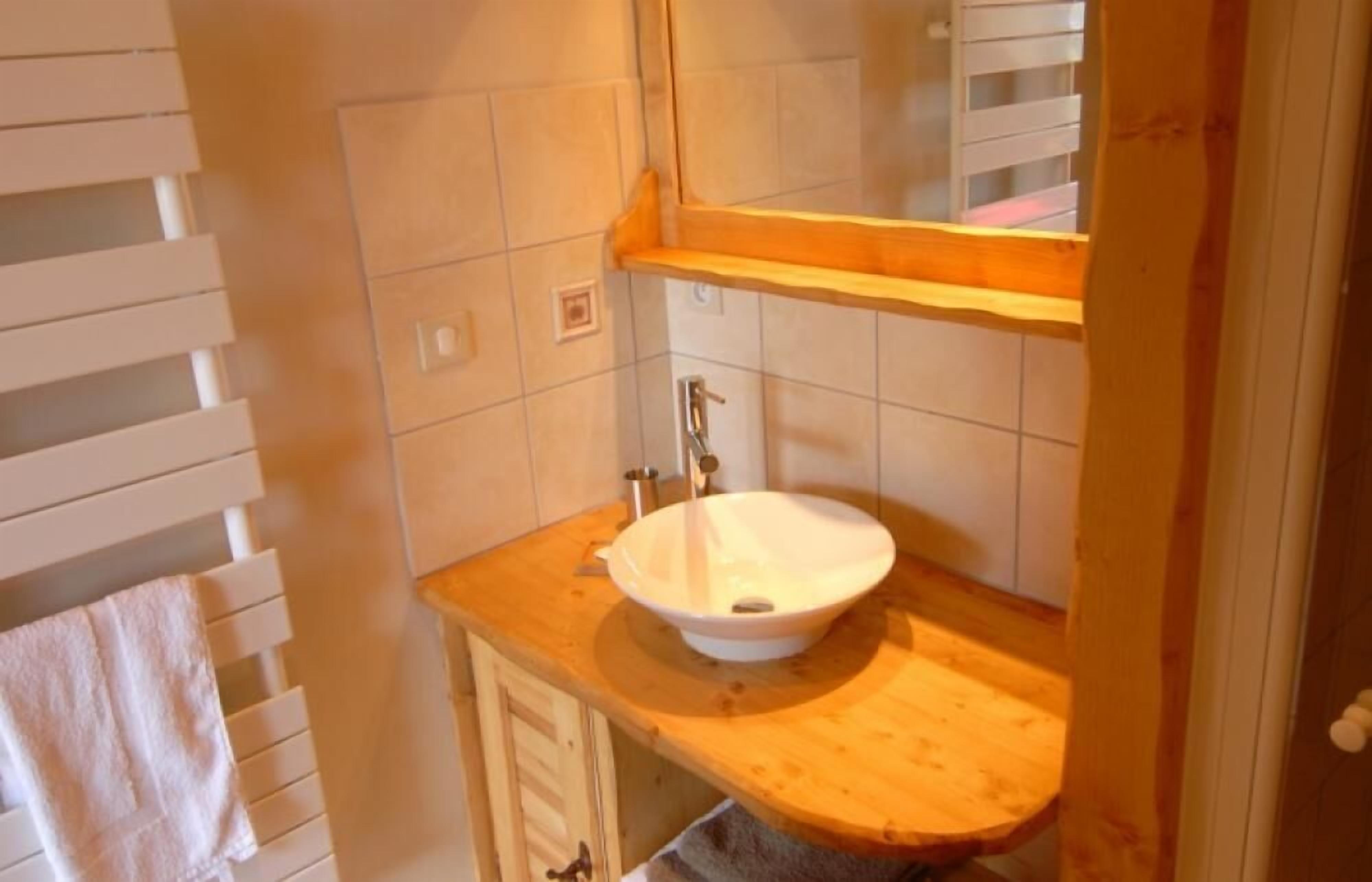 Une salle de bain avec un meuble-lavabo en bois, un lavabo blanc et un miroir au-dessus.