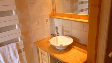 A bathroom with a wooden vanity, a white sink, and a mirror above it.
