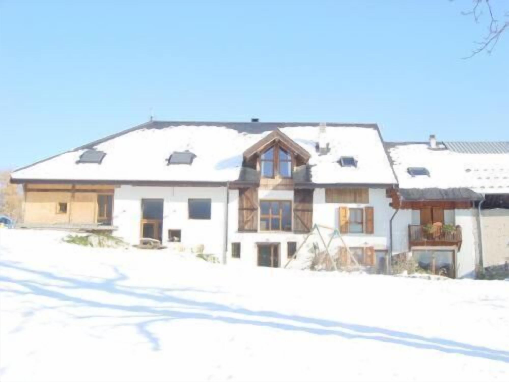 A two-story house with a sloped roof, multiple windows, and a visible balcony.
