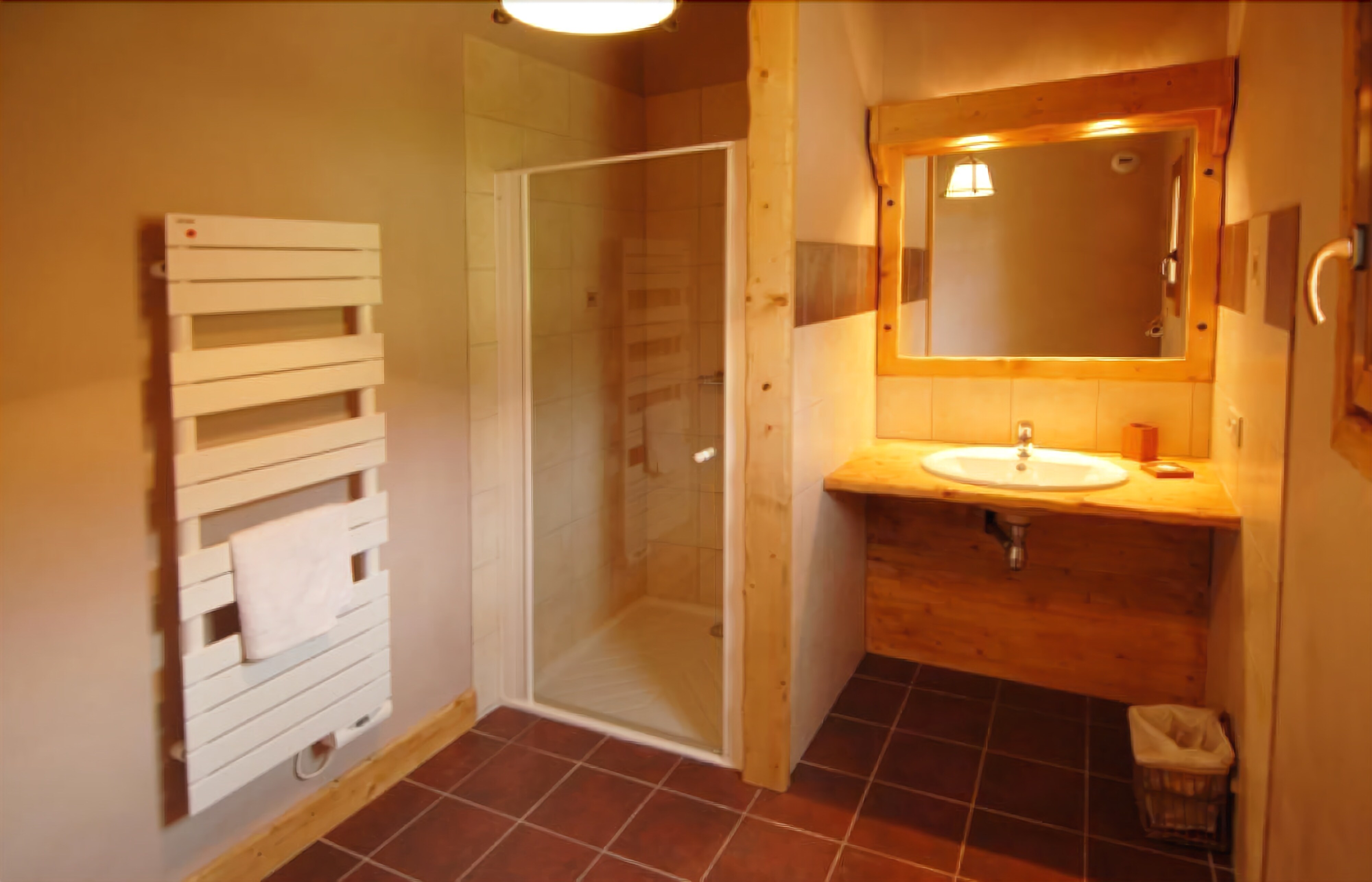 A bathroom with a glass shower enclosure, a wooden vanity with a sink, and a towel rack.