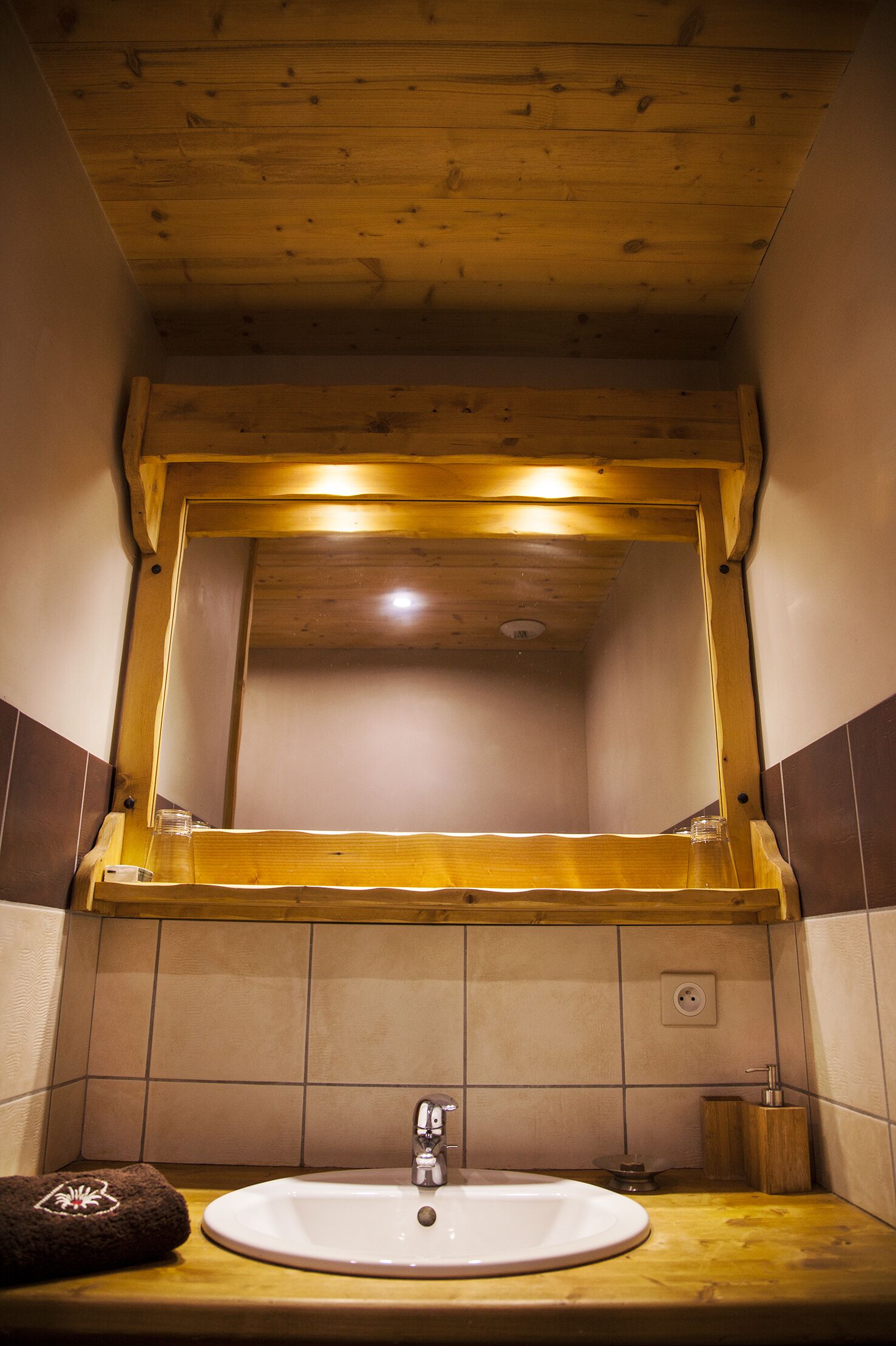Un bagno con soffitto in legno, un grande specchio, un lavandino e un asciugamano sul ripiano.