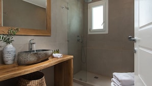 A modern bathroom with a wooden vanity, a large mirror, a stone sink, and a glass-enclosed shower. - Villa Delmar - Delmar Collection (Milos)