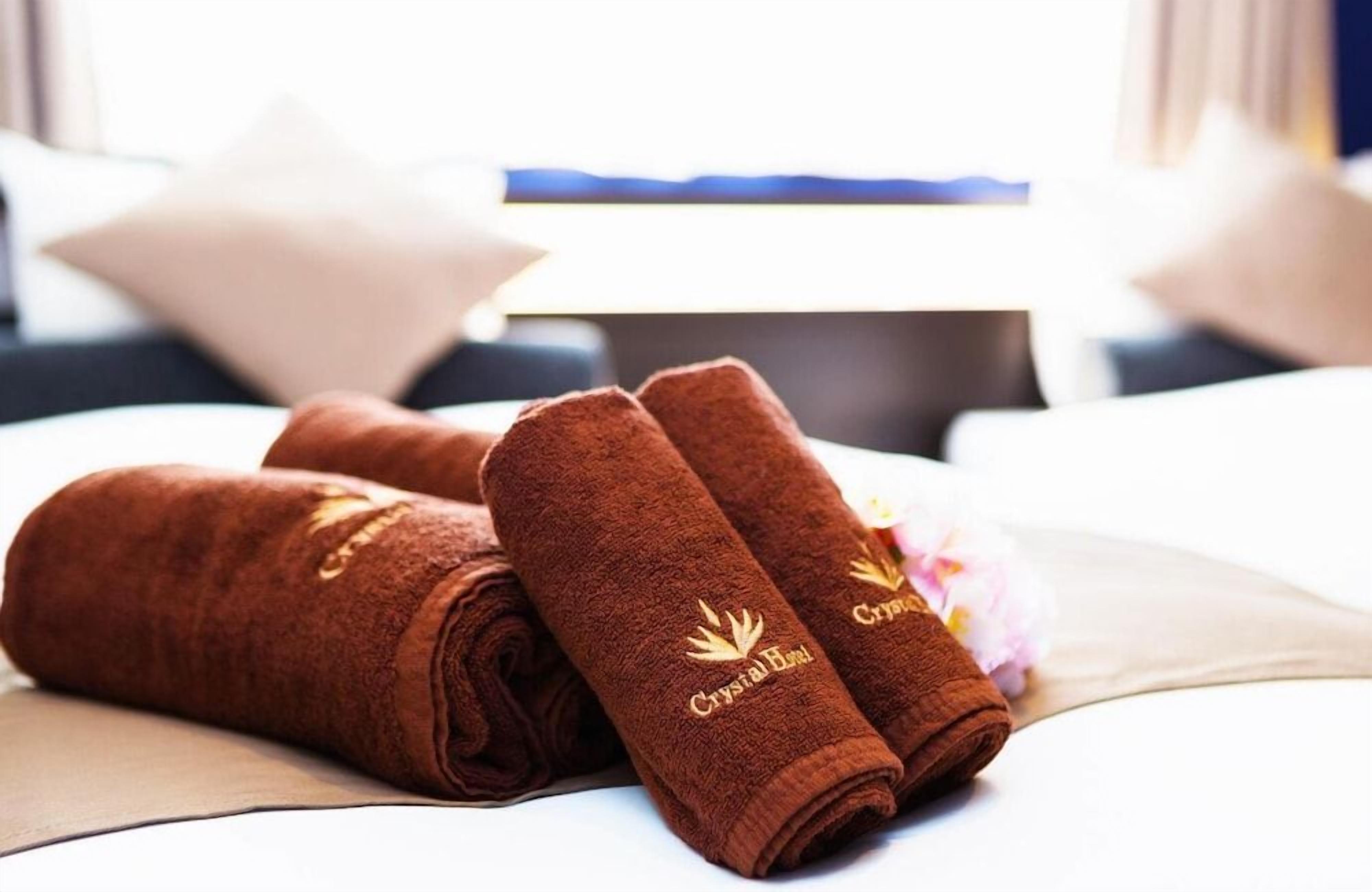 A bed with a neatly folded brown towel and a pillow.