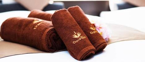 A bed with a neatly folded brown towel and a pillow.