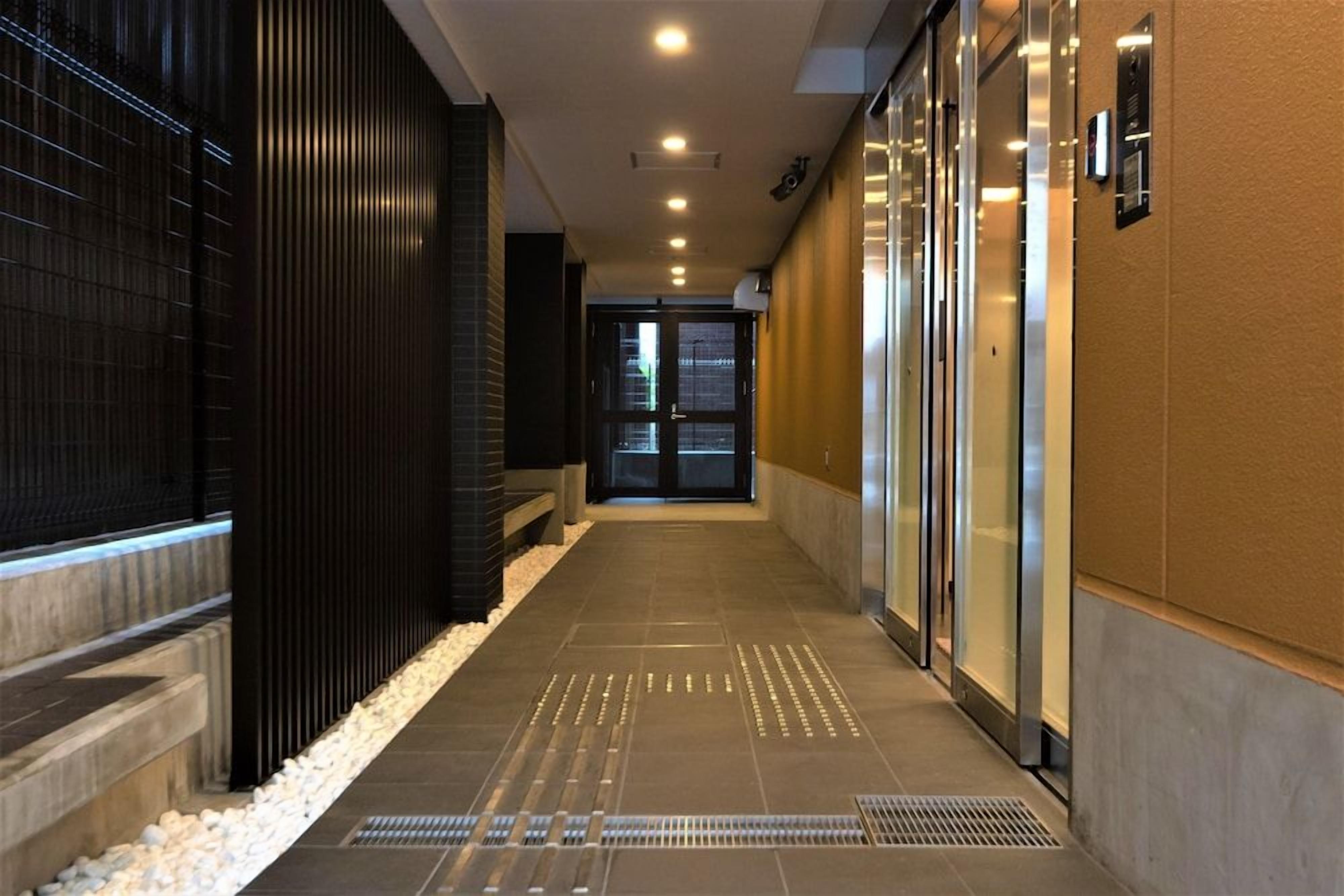 A corridor with a tiled floor, a metal grate, and a door at the end.