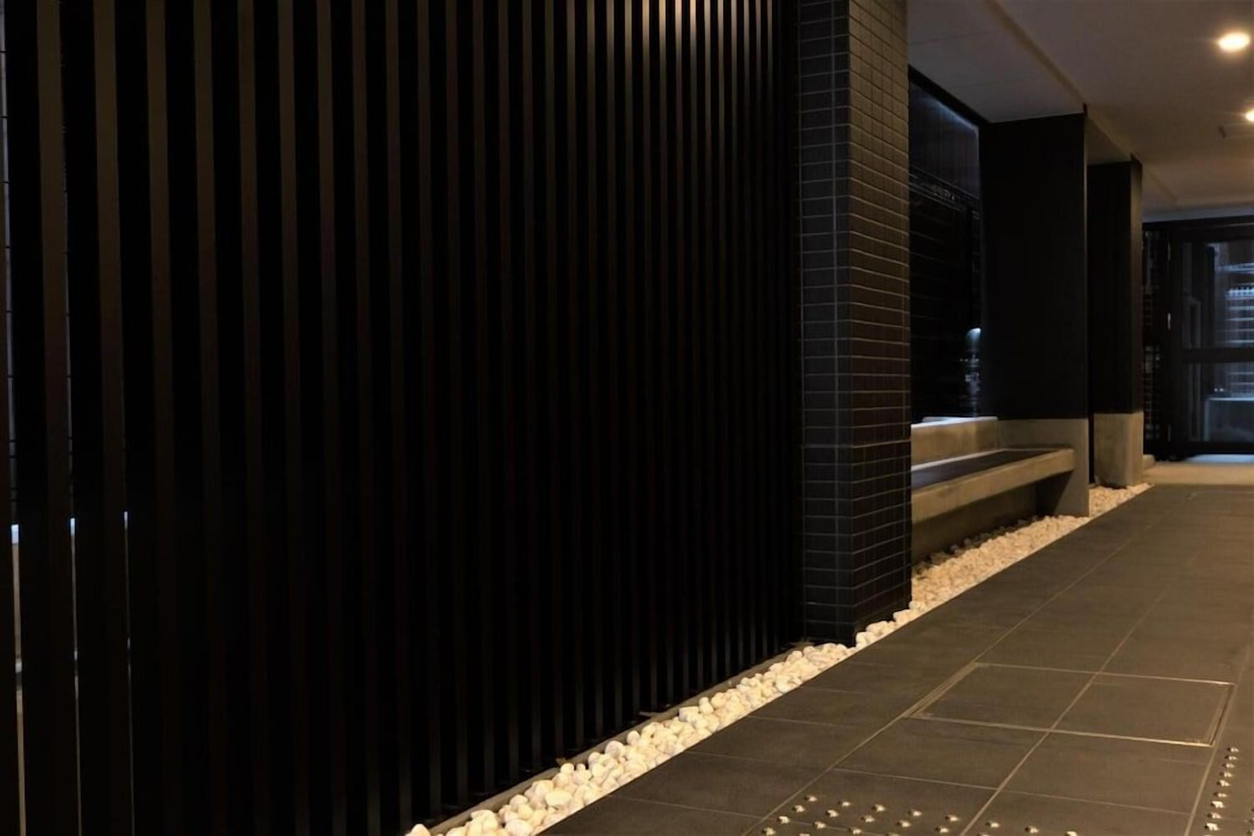 A corridor with a dark vertical panel, a tiled floor, and a bench with steps.