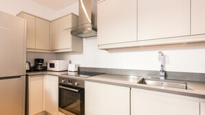 A modern kitchen with white cabinetry, stainless steel appliances, a built-in oven, and a microwave. - Eson 2 - The Westbourne Terrace Cocoon (London)