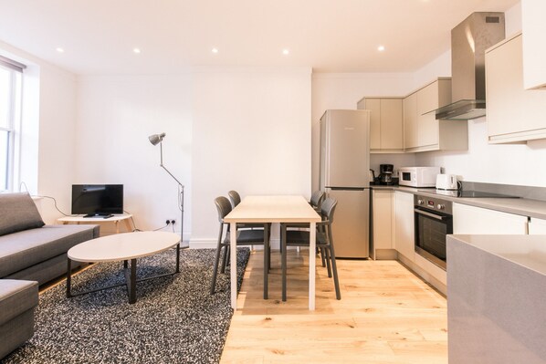 Un appartement moderne comprenant un espace de vie, une table à manger et une kitchenette.