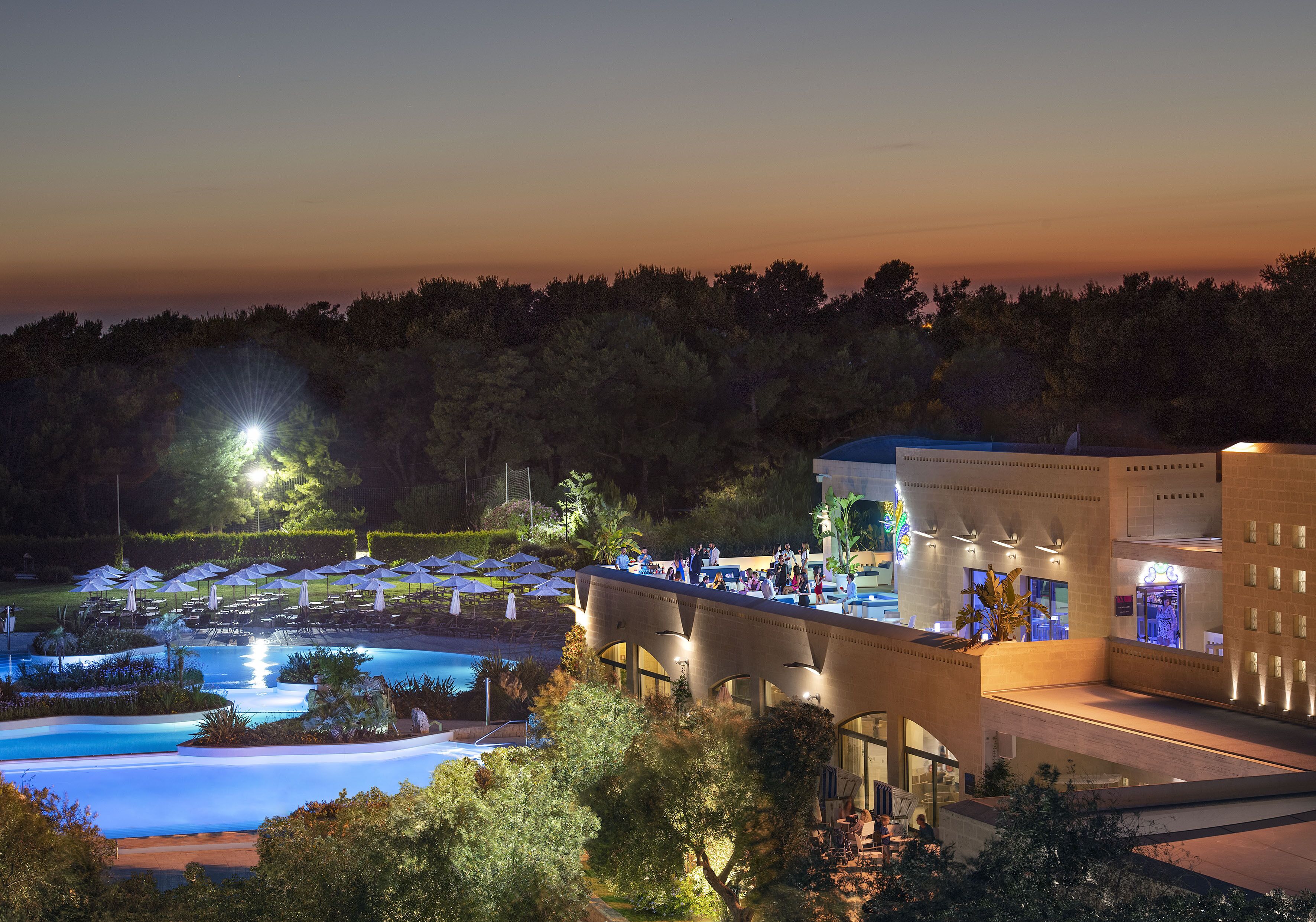 Un resort con piscina, mobiliario exterior y un paseo cubierto.