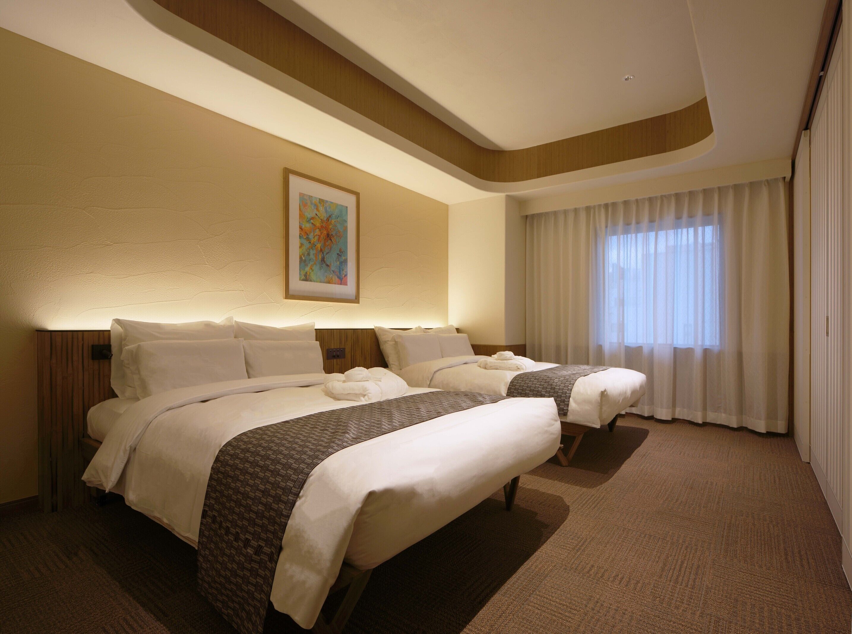 Habitación de hotel con dos camas, un cuadro en la pared y un ventanal con cortinas.