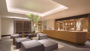 Una zona de recepción moderna con un mostrador de madera, asientos y una planta en maceta.