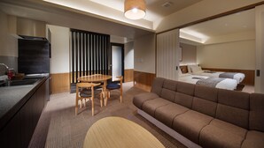Una habitación de hotel moderna con cocina, una mesa de comedor con sillas, un sofá y una cama.