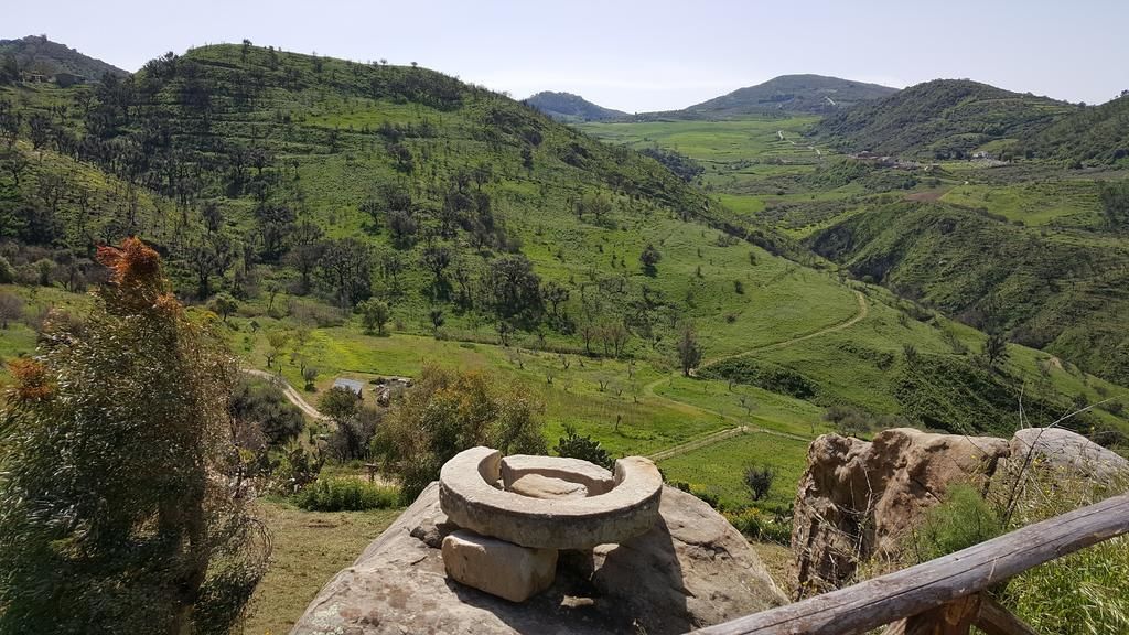A mountainous landscape with a circular stone structure in the foreground.