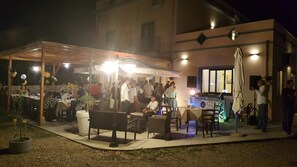 An outdoor dining area with tables and chairs, a covered seating area, and a grill station. - Agriturismo Mama Lina (Patti)