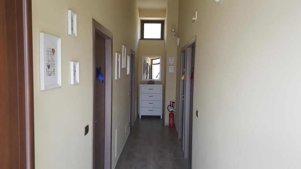 A narrow hallway with a fire extinguisher, a small window, and a door at the end.