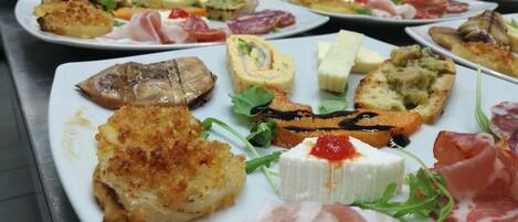 A buffet with various dishes including bread, cheese, and meats.