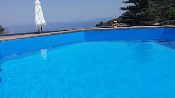 Una piscina al aire libre de temporada, sombrillas