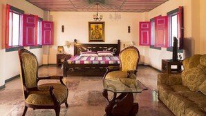 A bedroom with a bed, two chairs, a sofa, a glass coffee table, a TV, and a painting on the wall. - On Vacation Karlaka (Roncesvalles)