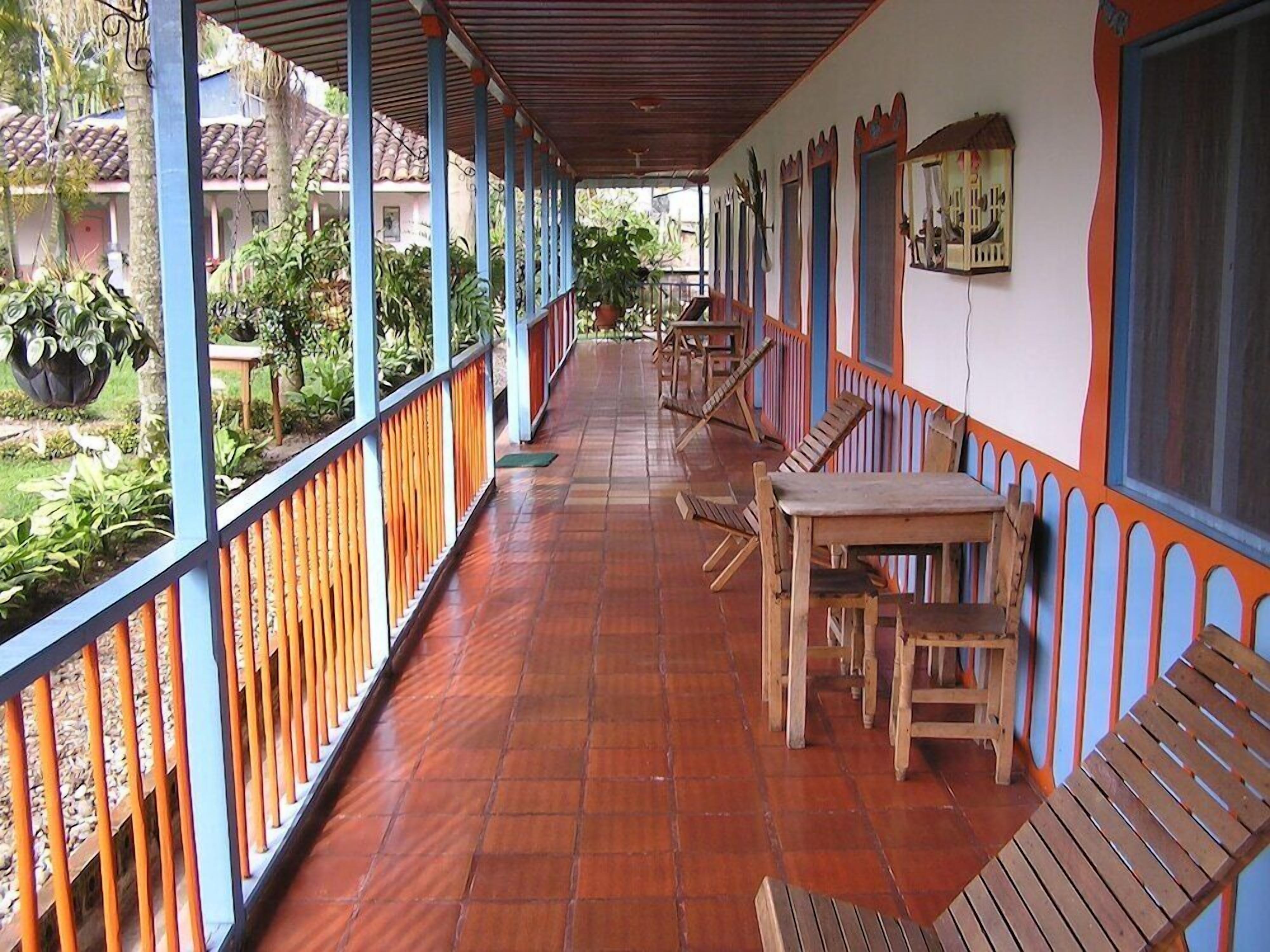 A covered outdoor area with wooden furniture and a tiled floor.