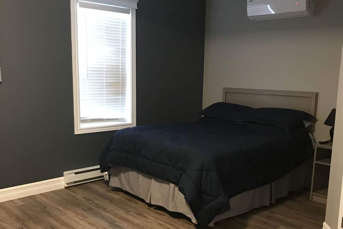 Un dormitorio con cama, ventana y aire acondicionado.
