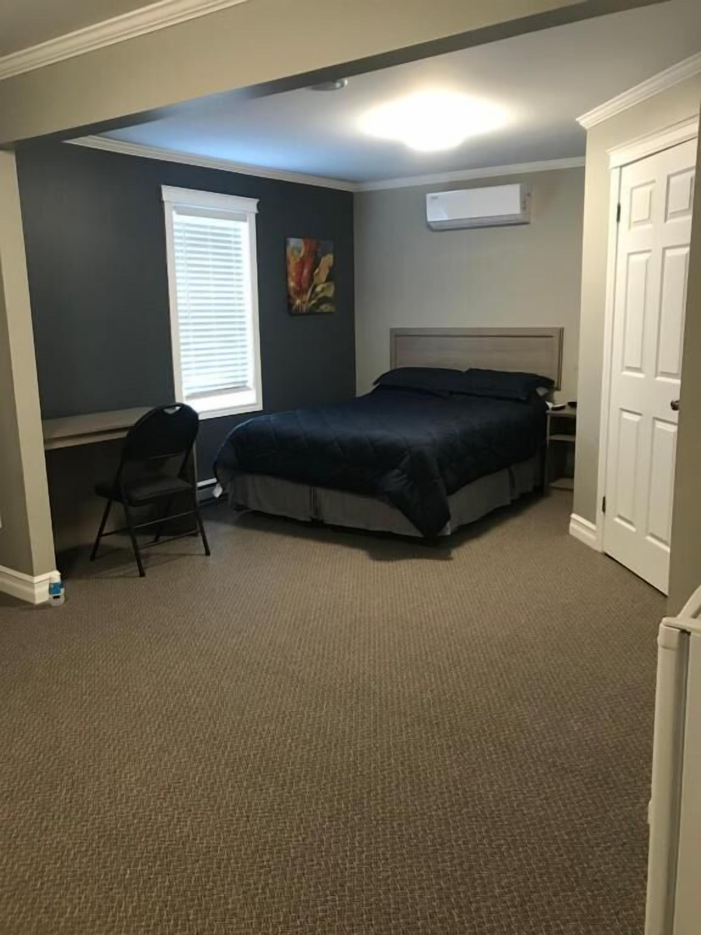 A bedroom with a bed, a desk, and a chair.
