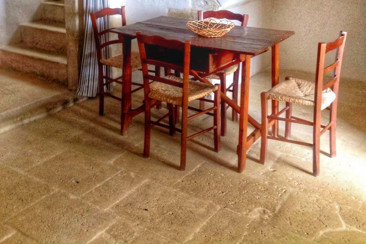 A dining area with a wooden table and chairs, a woven basket, and a staircase leading to an upper level.