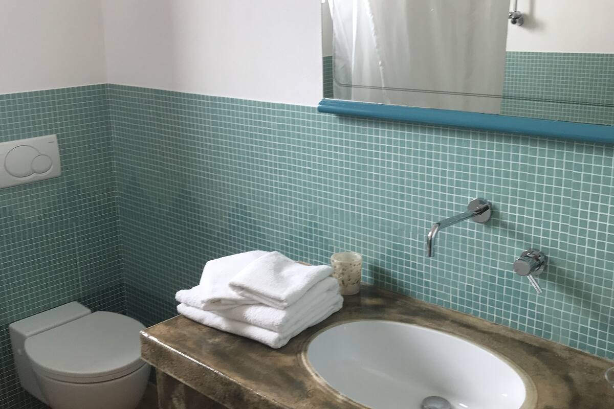 Een badkamer met een wit toilet, een wastafel met een marmeren blad en een spiegel boven de wastafel.