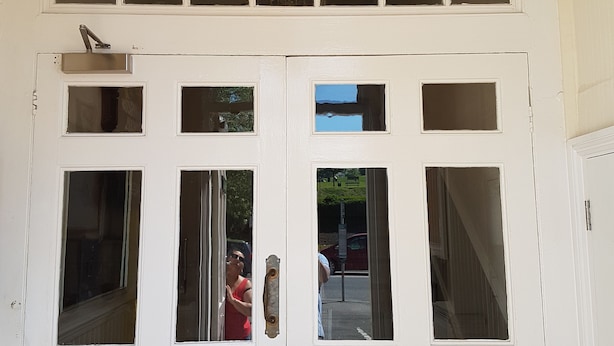 A white double door with multiple windows and a brass chandelier above. - Apartment 9 Robertson Villas (Rochester)