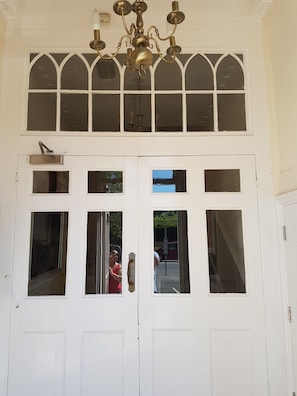 A white double door with multiple windows and a brass chandelier above. - Apartment 9 Robertson Villas (Rochester)