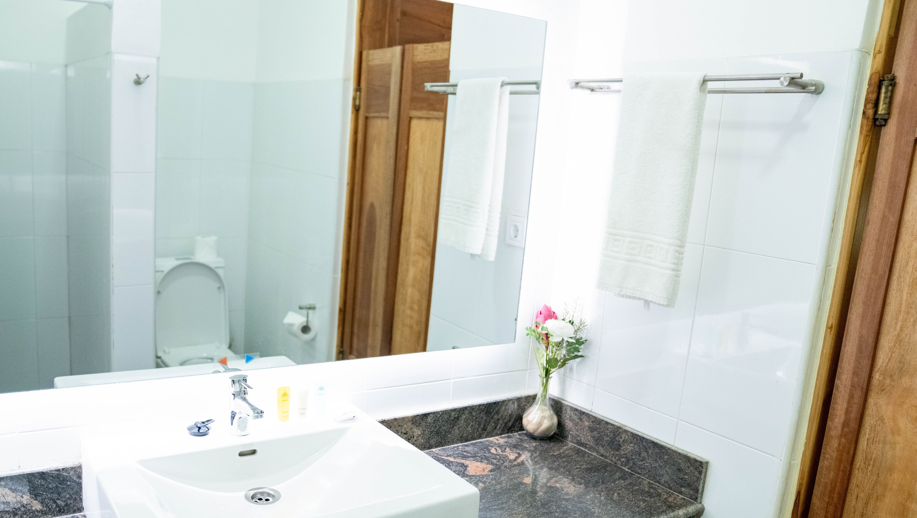 A bathroom with a white sink, mirror, and towel rack.