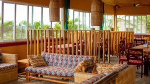 A spacious indoor area with wicker furniture, large windows, and a wooden ceiling.