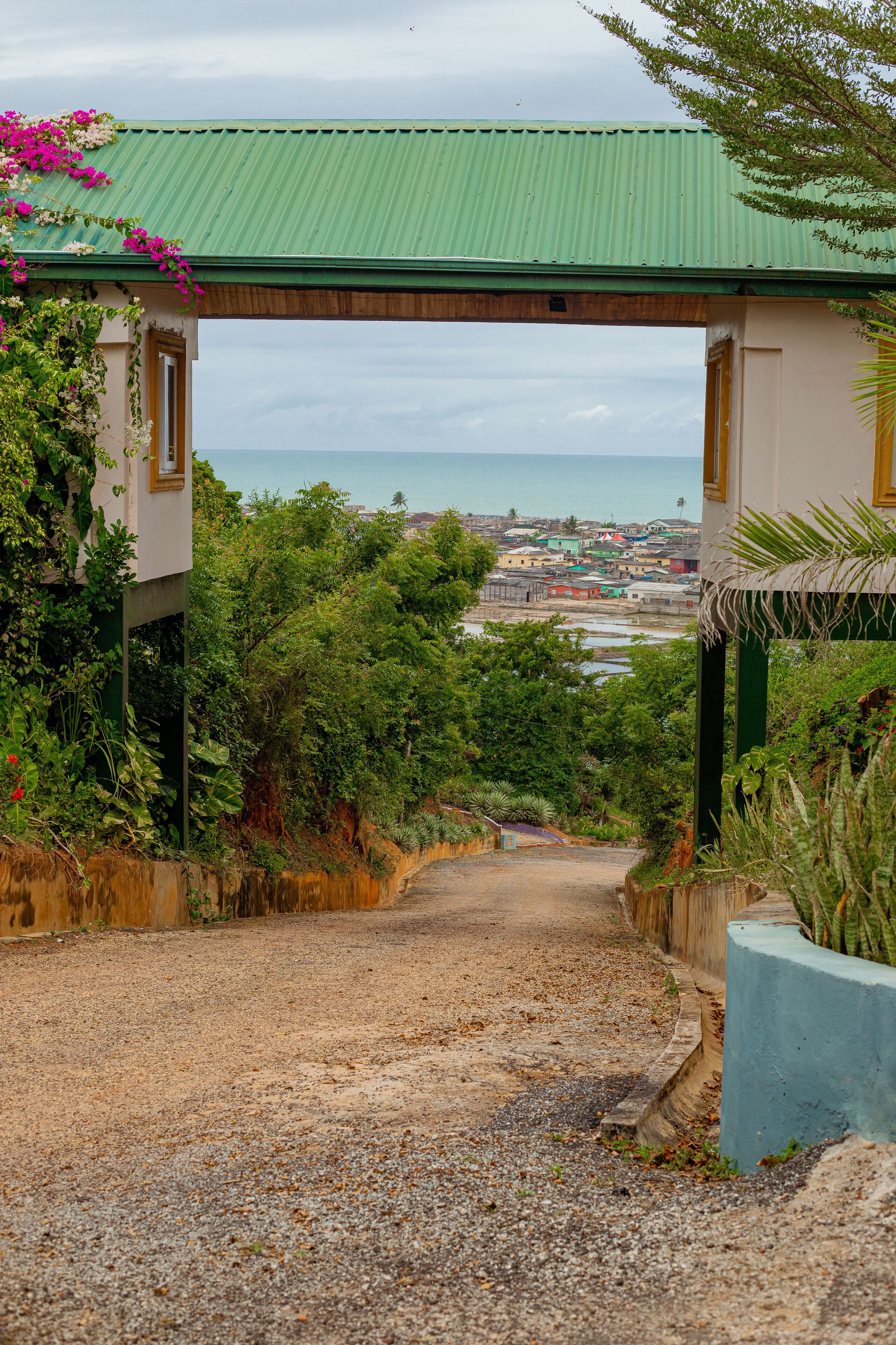 Un sendero de grava conduce a un edificio con techo verde y vistas al mar.