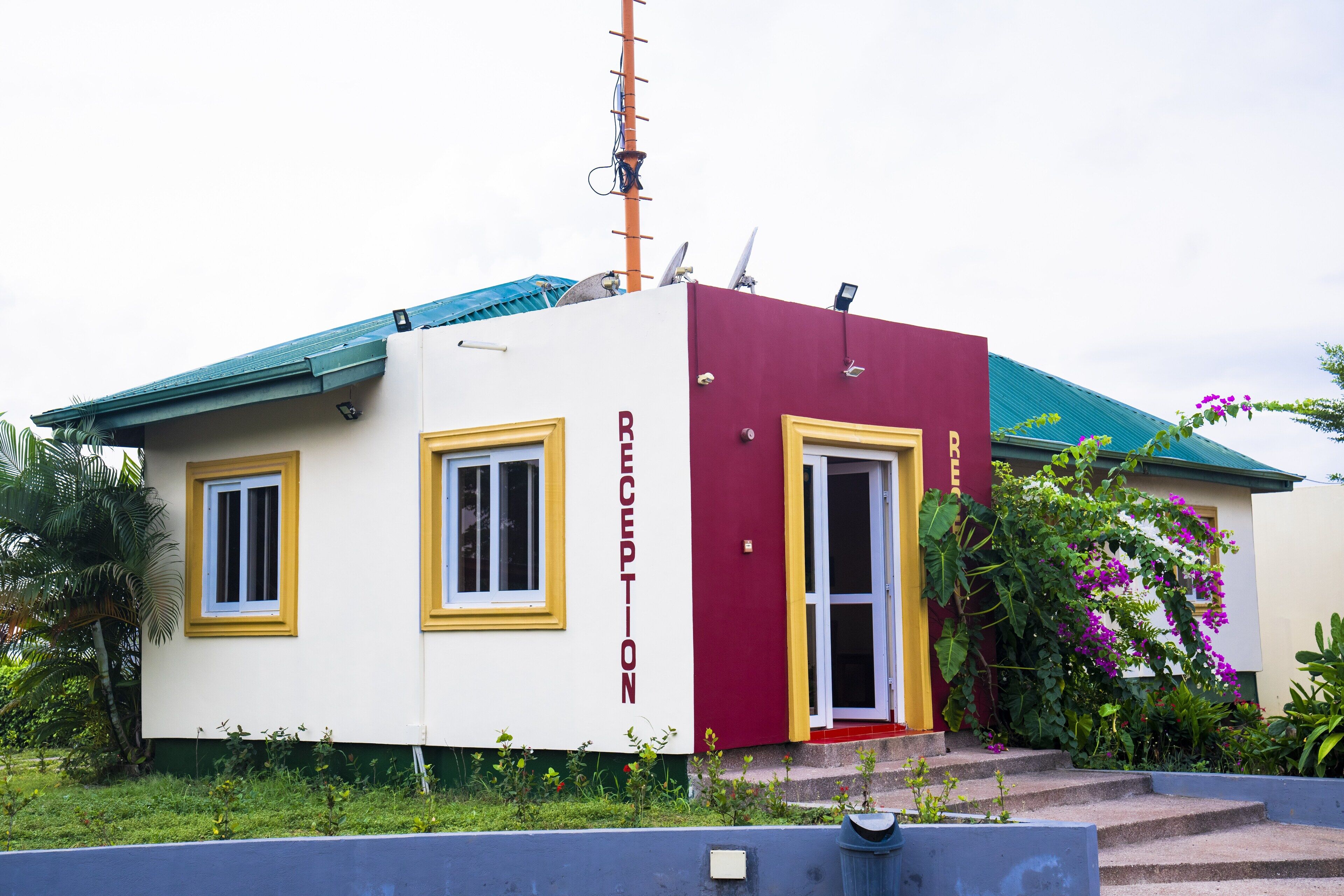 A reception building with a red and white facade, a blue roof, and a satellite dish on the roof.