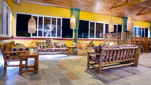 A spacious lounge area with wicker furniture, large windows, and hanging wicker lamps.