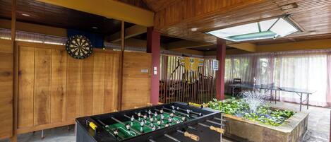 A wooden-floored indoor area with a foosball table and a small water feature.