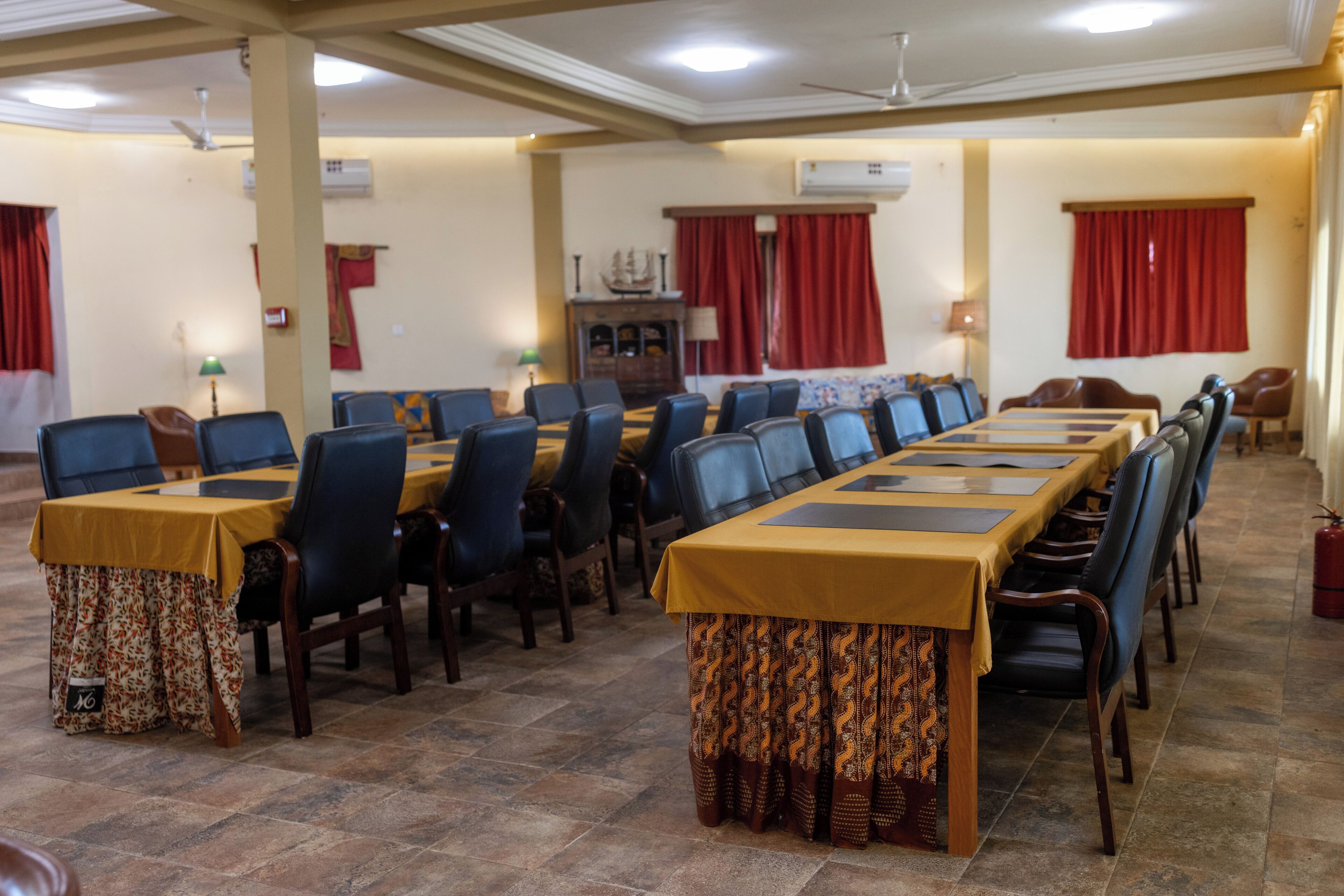 A conference room with a long table, multiple chairs, and a patterned tablecloth.