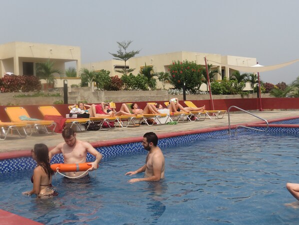 A swimming pool area with lounge chairs and a poolside view. - Golden Hill Parker Hotel (Elmina)