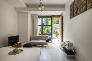 Et moderne hotelværelse med seng, fjernsyn, sofa og udsigt til grønne områder.