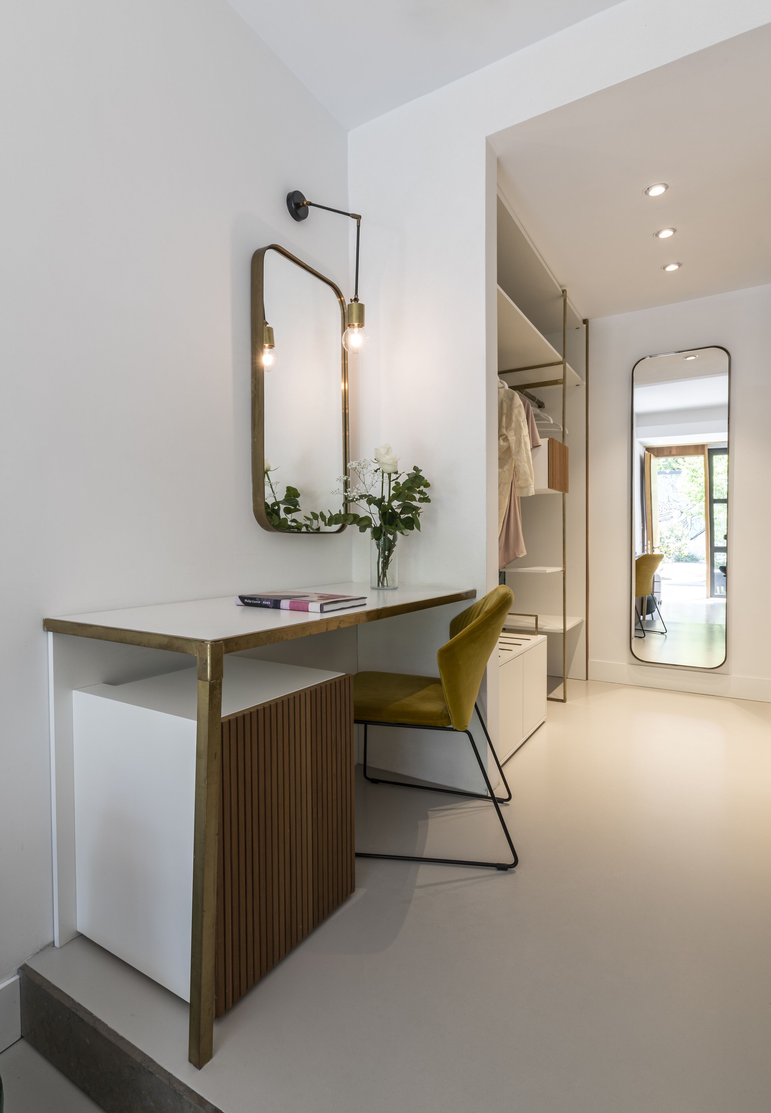 Ein modernes Zimmer mit einem weißen Schreibtisch, einem gelben Sessel, einem Spiegel und einem Kleiderschrank.