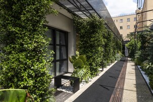 En smal sti omkranset af frodig vegetation og en moderne bygning med store vinduer.