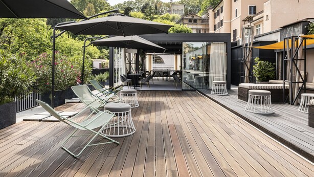 Une terrasse extérieure avec un sol en bois, des chaises longues et des parasols.