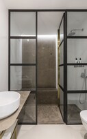 Et moderne badeværelse med brusekabine i glas, en stor vask og et toilet.