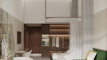 A modern bathroom with a freestanding bathtub, a green sofa, and a wooden wardrobe with hanging clothes.