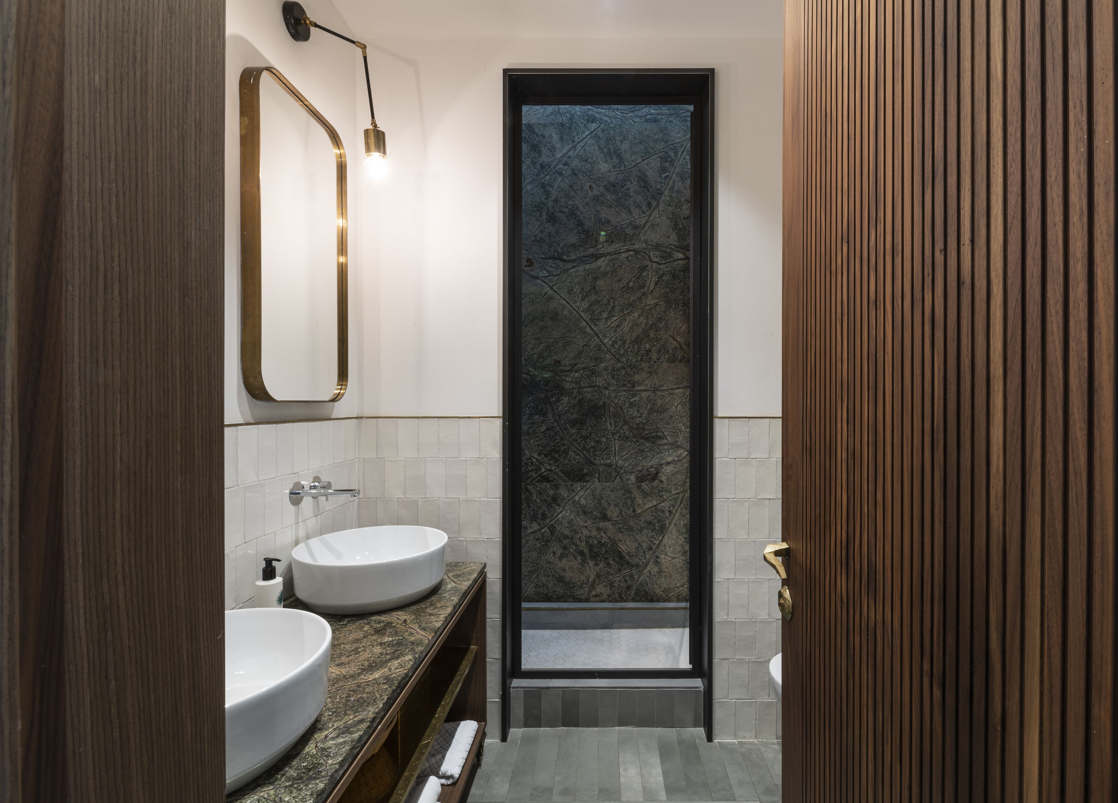A modern bathroom with two sinks, a large mirror, and a shower area.