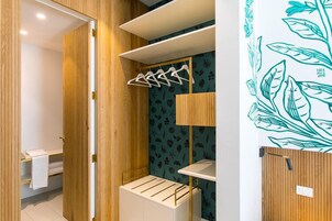 A modern bathroom with wooden cabinetry, a towel rack, and a shelf with a towel.