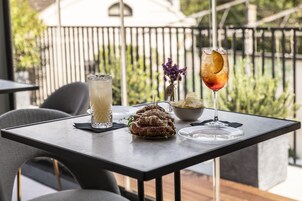 A table with a glass of iced beverage, a bowl of chips, and a plate of food.