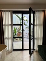 A room with a sliding glass door leading to an outdoor area with potted plants and a tiled patio.