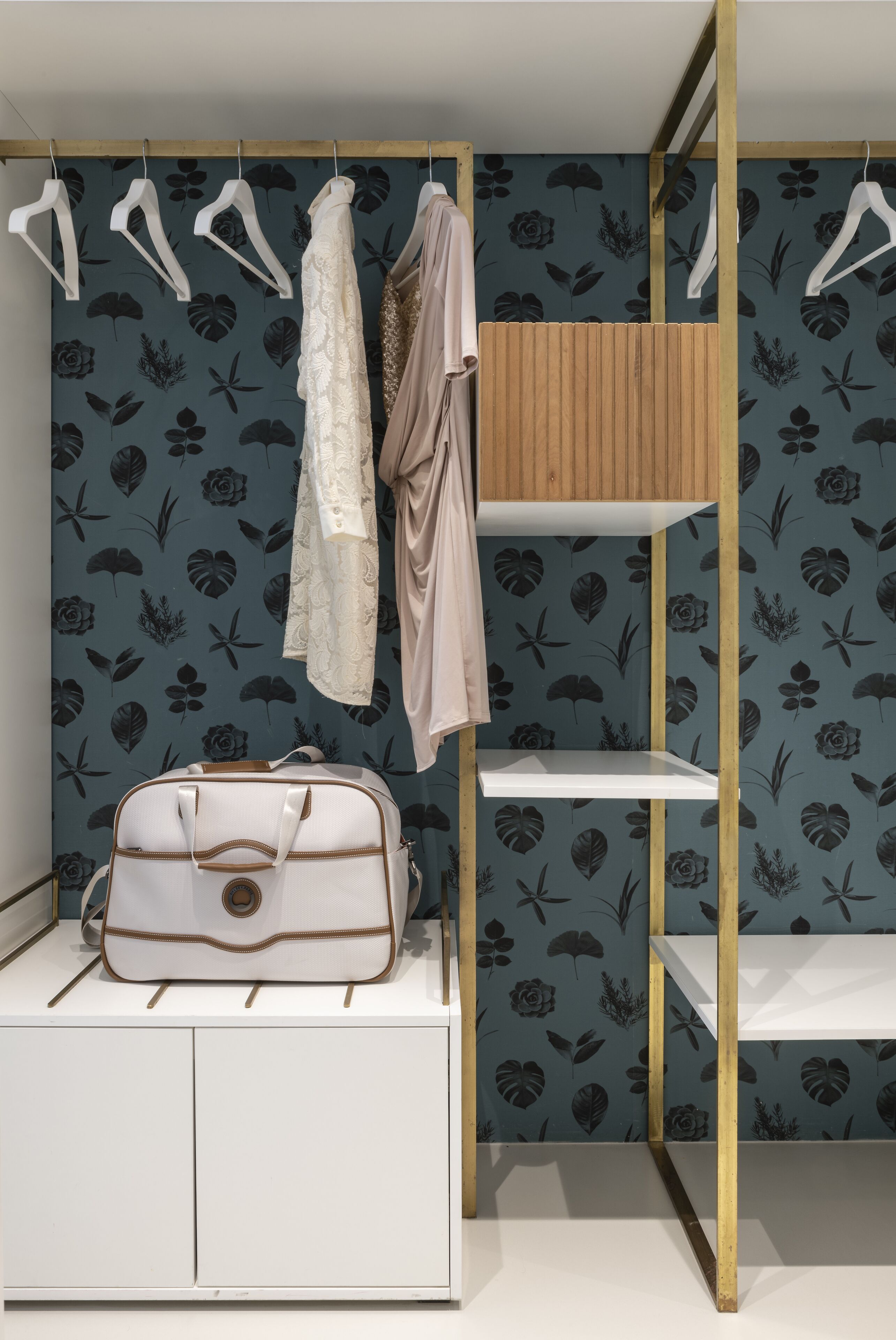 A room with a bunk bed, a wardrobe with hanging clothes, and a small table with a bag.