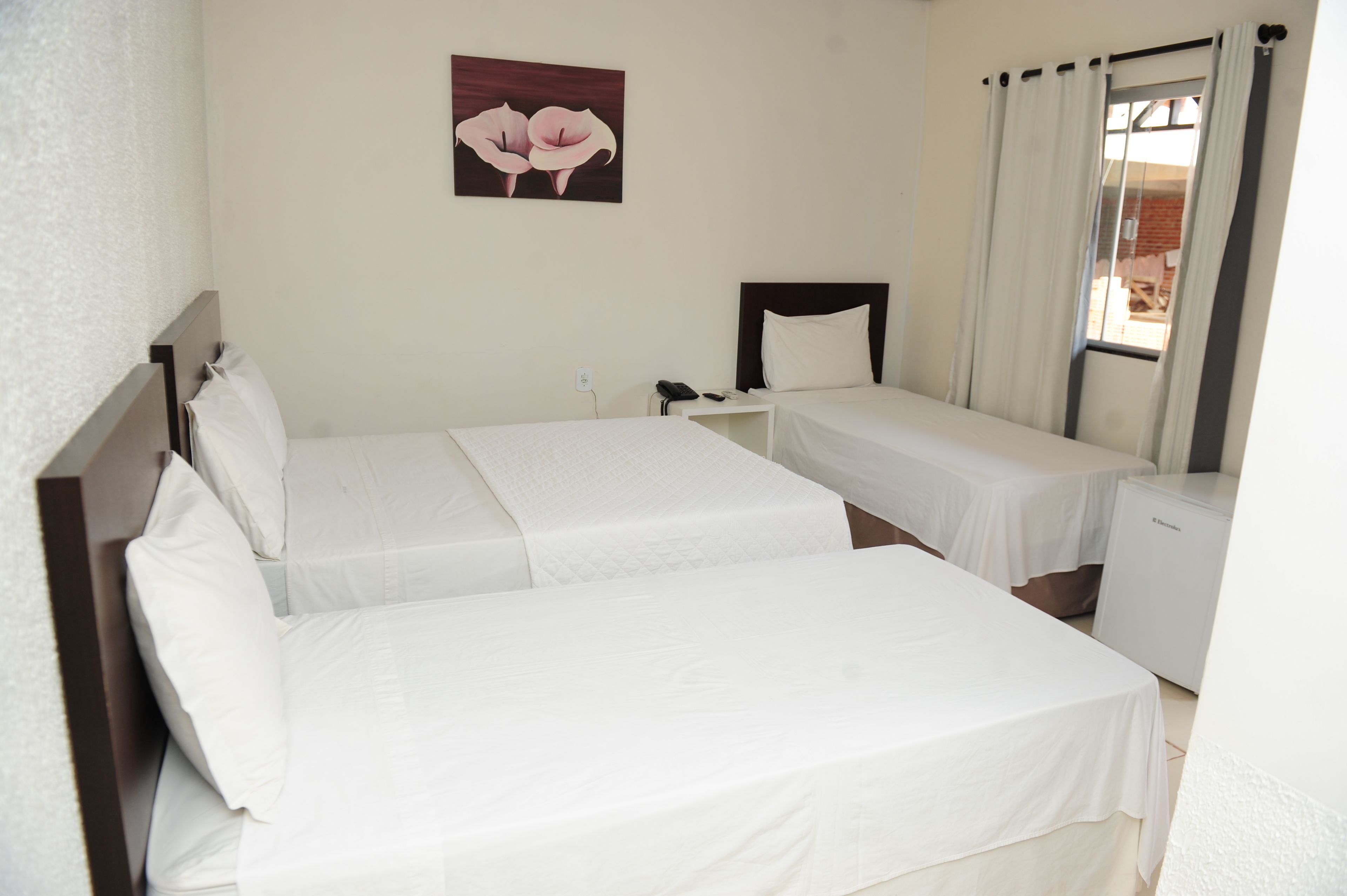 Une chambre d’hôtel avec deux lits simples, un petit bureau, une table de chevet, un téléphone et un tableau accroché au mur.